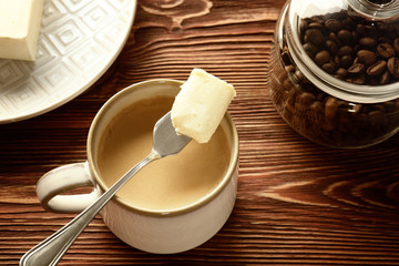 Cup of tasty butter coffee and shovel on wooden table