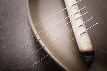 Plate with moxa stick and needles for acupuncture on dark textured background, closeup