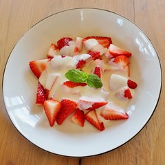 Dessert with strawberries, vanilla cream and decorated with a mint leaf
