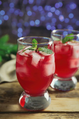 Glasses of delicious wine spritzer on blurred lights background
