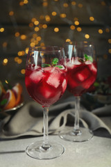 Glasses of delicious wine spritzer on blurred lights background