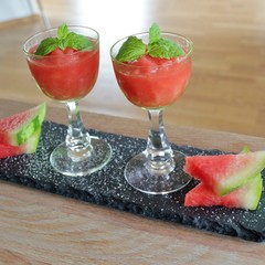 Tray with two glasses of watermelon granita decorated with mint leaves and slices of watermelon
