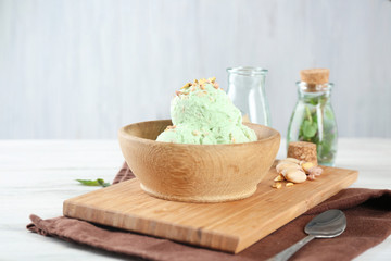 Bowl with delicious pistachio ice cream on wooden board