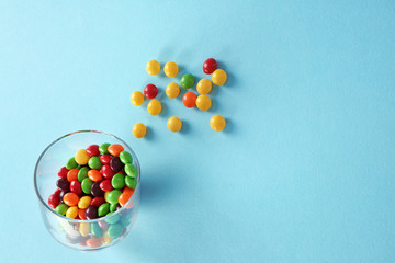 Delicious colorful candies in bowl on color background