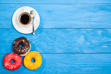 Obraz na płótnie Canvas Cup with coffee and donuts on a blue wooden table