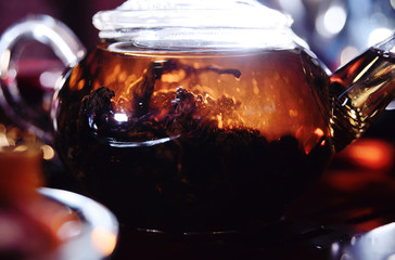 Fresh black leaf tea in a glass kettle close-up on a tea table. tea ceremony