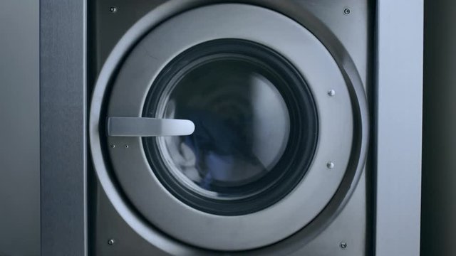 Industrial washer machine working. Clothes laundry machine. Close up of laundry clothes in industry washing machine. Working washing machine. Closeup of clothes washer. Laundry clothes washing