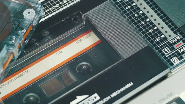 Playing an Audio Cassette in a Vintage Tape Recorder. Close-up. Black audio cassette with film rotates inside the deck. Red Record level indicator on a Vintage Cassette Deck.