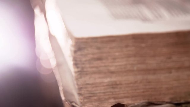 very old book with broken pages in a library. The book seems to be from the 17th or 18th century. Video clip in 4K resolution with a impressive lighting.
