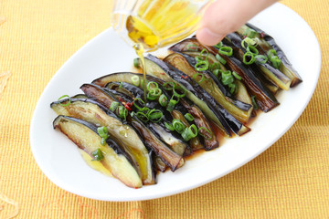 Grilled eggplants with oil and onion on white platter