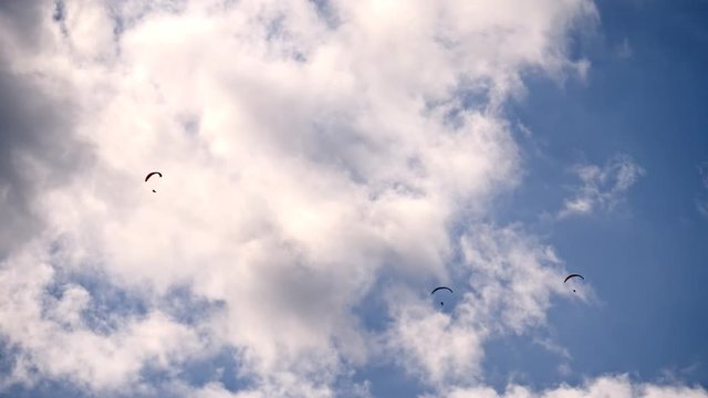 three sports hang gliders flying overhead
