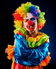 Sad clown on black background. Portrait of sick woman holds on to stomach after performance.