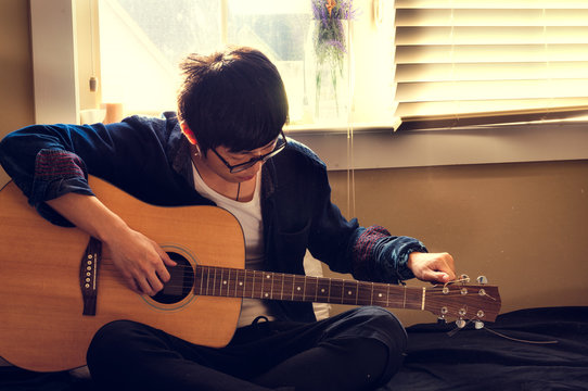 Young Man Tunning a Guitar