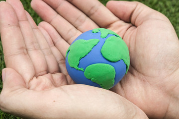 Globe ,earth made from clay in hand on green background. Concept Save green planet. Earth day holiday concept