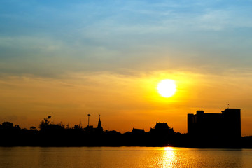 silhouette of building on sunset against lake