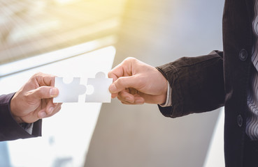 Businessmen hold jigsaw puzzles for each other. Business teamwork concept