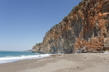 Fototapeta na wymiar Beautiful sand and pebble beach behind red rock