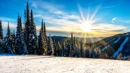 Sunset over the snow covered hills surrounding the alpine ski village of Sun Peaks in the Shuswap...