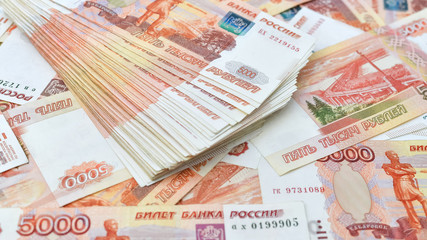 denominations of five thousand rubles scattered on the table, a widescreen background.