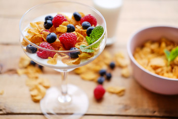 Crunchy corn flakes with some wild berries in a glass cup.