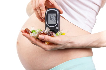 Pregnant woman with glucometer and colorful candies, diabetes and healthy nutrition during pregnancy