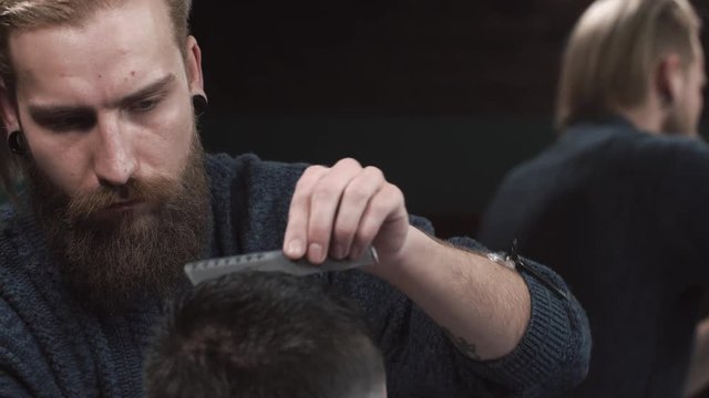 Male barber cutting hair of man in Barbershop