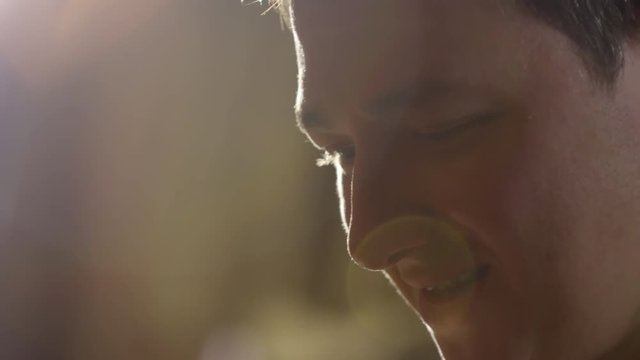 Closeup of young man in chef uniform and white toque on his head smiling at work