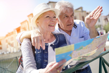 Senior couple of tourists looking at city map