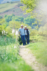 Senior couple walking in country track by sunny day