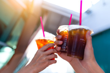 Friends holding iced coffee with sun flare