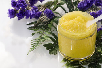 Transparent jar with yellow contents on leaves and flowers