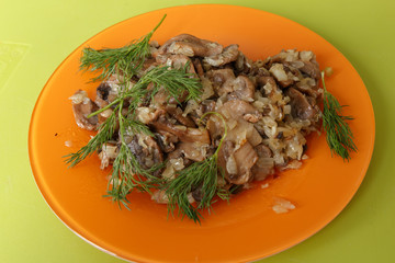 Fried mushrooms with onions and spices in an orange dish dill -decorated