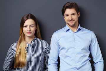 mann und frau stehen nebeneinander vor einer grauen wand