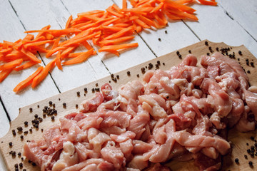 On this photo cutting meat lying with vegetables on wood desk.