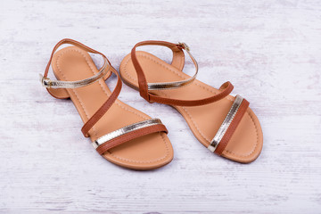 Pair of women's sandals on a white wooden background