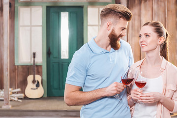 happy man and woman embracing and holding wine in wineglasses