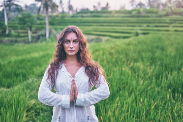 Fototapeta na wymiar Yoga with view of green fields. Young woman with clasped hands. Concept of calm and meditation.