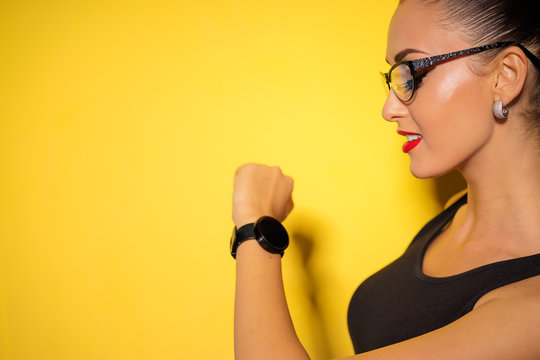 Close up studio portrait of attractive businesswoman looking at smartwatch on her hand.