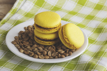 Yellow macarons on the plate with green coffee beans