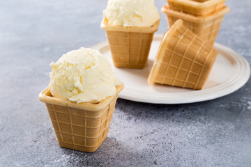 Waffle cups with homemade vanilla ice cream on gray ctone background. Summer food concept.