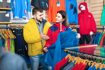 Fototapeta premium Couple examining track jackets in sports clothes store