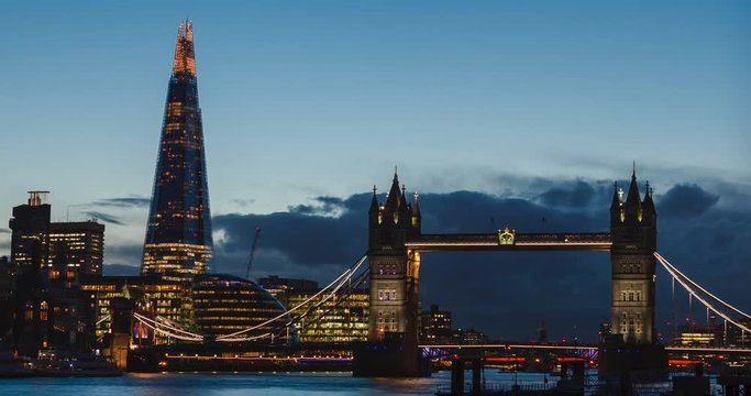 Evening time-lapse of the Shard and Tower Bridge with blue sky.