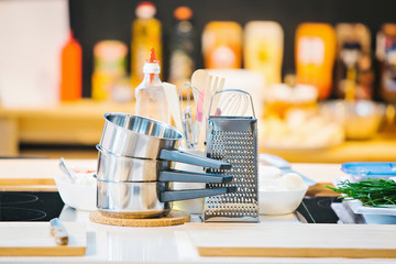 Dishes: pots with handles and a grater on the table.