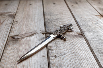 stiletto inlaid with carved arm rests on a wooden table surface