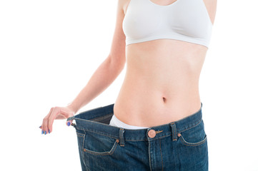 sport, fitness and diet concept - close up of trained belly with big old jeans