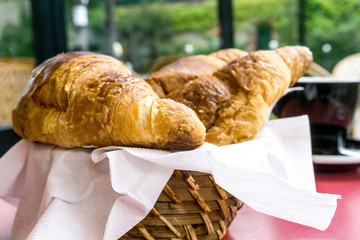 Breakfast with coffee and croissants in a basket on table