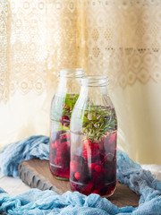 Detox infused water with berries and rosemary herb on wooden background