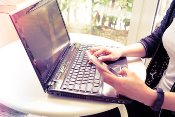 Young student women hold smart phone while using laptop computer