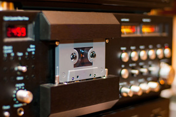 Old compact audio cassette in vintage audio system with tape recorder