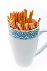 pretzel sticks in a cup on white background